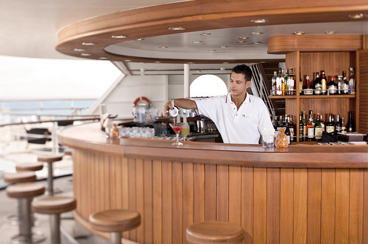 Bartender pouring tropical cocktails at beautiful hardwood ladened round bar.